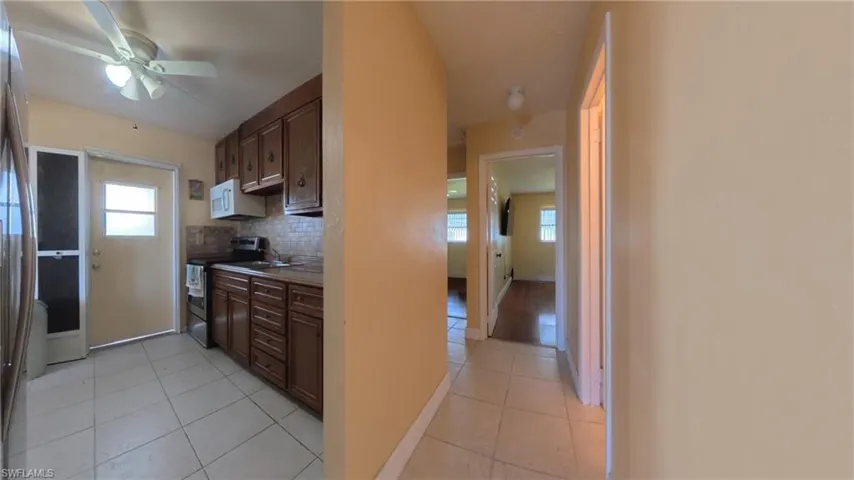Kitchen featuring tasteful backsplash, stainless steel appliances, dark brown cabinets, light tile patterned floors, and ceiling fan