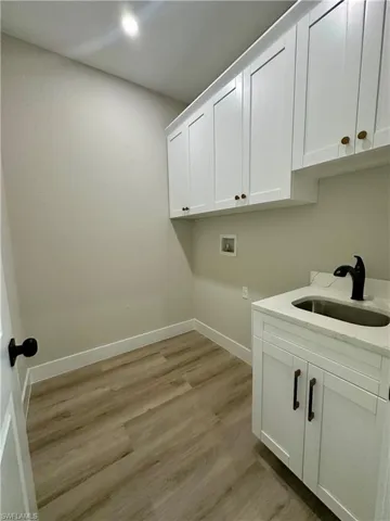 Laundry room with hookup for a washing machine, light wood-style flooring, and cabinet space
