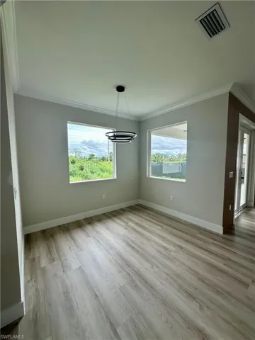 Unfurnished dining area featuring crown molding, wood finished floors, and plenty of natural light