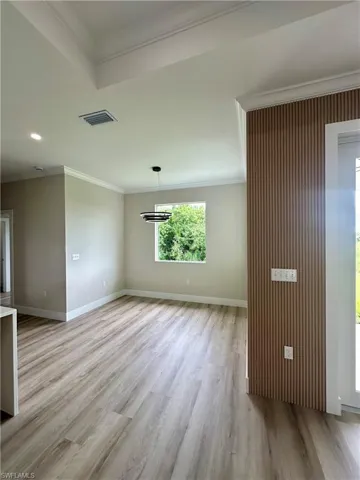 Empty room featuring crown molding, light wood-style flooring, and recessed lighting