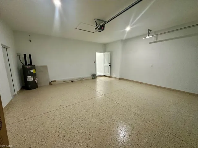 Garage featuring electric water heater and baseboards
