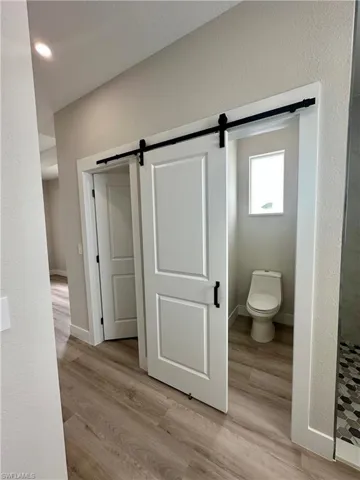 Bathroom with a walk in shower, wood finished floors, and recessed lighting