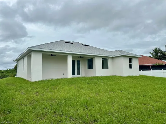 Rear view of property with a ceiling fan, stucco siding, french doors, and roof with shingles