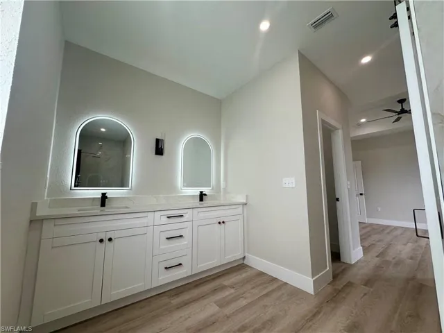 Full bathroom featuring walk in shower, double vanity, and wood finished floors