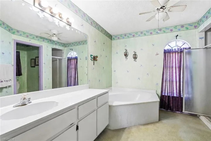 VIRTUALLY STAGED Double vanity with integrated sinks and white cabinetry, accompanied by a corner soaking tub and a separate shower enclosure