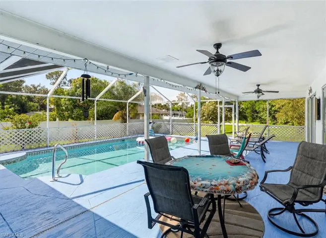 VIRTUALLY STAGED Screened-in pool area featuring a rectangular pool, concrete decking with blue finish, and multiple ceiling fans