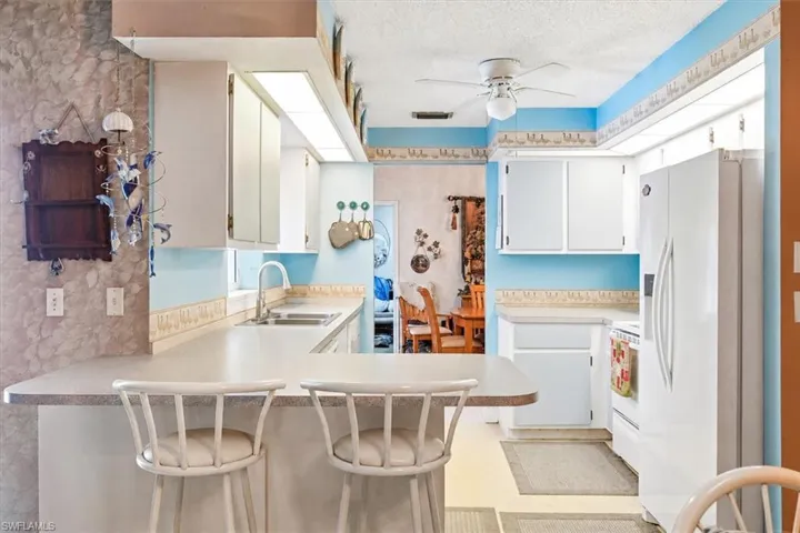 VIRTUALLY STAGED Kitchen featuring white cabinetry, light-toned countertops, and a double basin sink with a gooseneck faucet