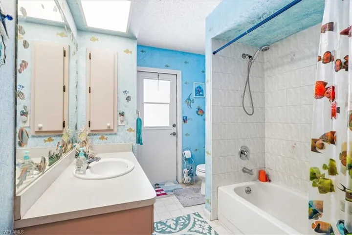 Bathroom featuring a single vanity, built-in storage cabinets, a combination shower and tub, and a windowed exterior door
