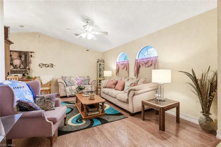 Living area featuring vaulted ceilings, wood-finish flooring, and two arched windows