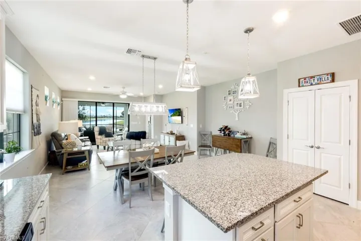 Kitchen with light stone countertops, white cabinets, a kitchen island, and ceiling fan