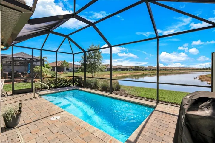 Swimming pool featuring a sunroom, glass enclosure, a grill, and a patio area