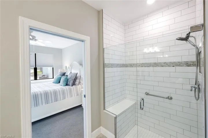 Ensuite bathroom featuring a shower stall, carpet flooring, and ceiling fan