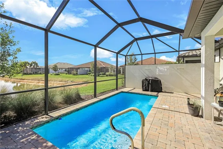 Outdoor pool featuring a sunroom, a lanai, a lawn, and a patio area