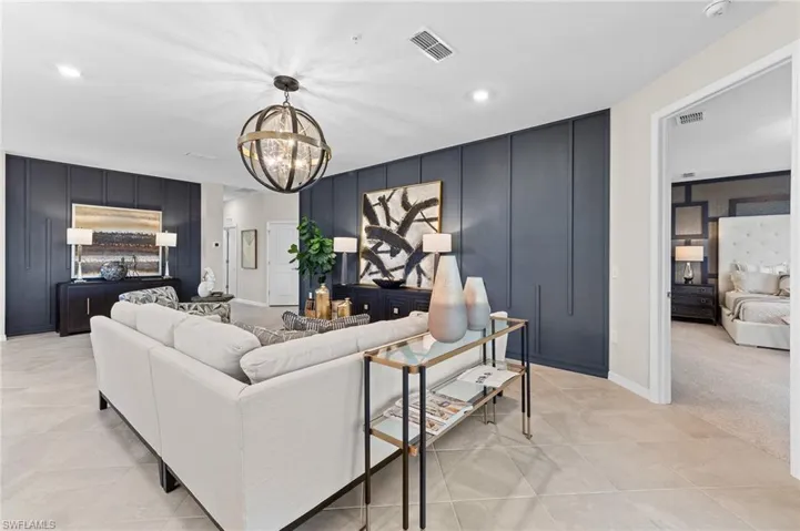 Living area with a decorative wall, a chandelier, an accent wall, recessed lighting, and light colored carpet