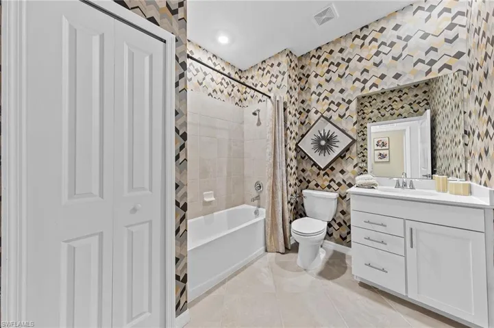 Full bathroom featuring vanity, shower / bath combo with shower curtain, light tile patterned floors, a closet, and wallpapered walls