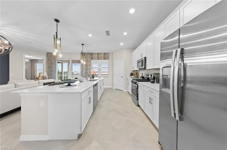 Kitchen featuring appliances with stainless steel finishes, white cabinetry, open floor plan, recessed lighting, and a large island with sink