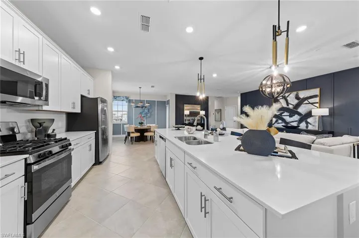 Kitchen featuring open floor plan, white cabinetry, appliances with stainless steel finishes, decorative light fixtures, and recessed lighting