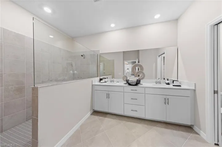 Full bathroom featuring double vanity, a walk in shower, and light tile patterned flooring