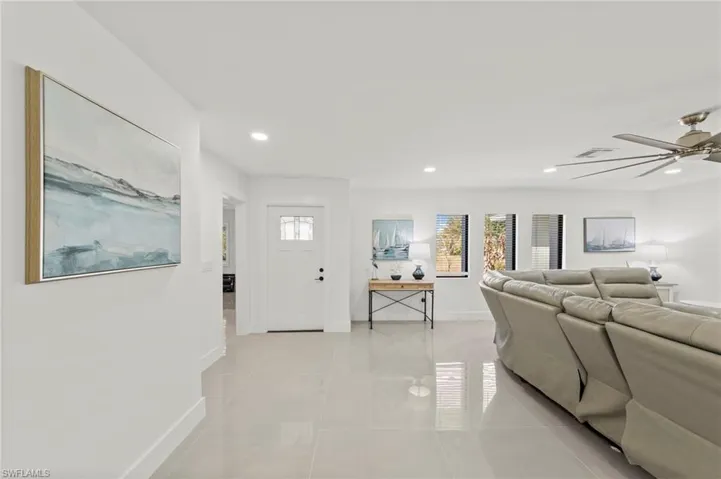 Living room with a ceiling fan, light tile patterned floors, and recessed lighting