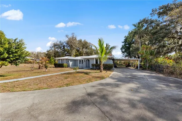 Ranch-style home featuring concrete driveway, a front lawn, a carport, and stucco siding