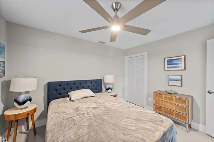 Bedroom with a closet, ceiling fan, and concrete flooring