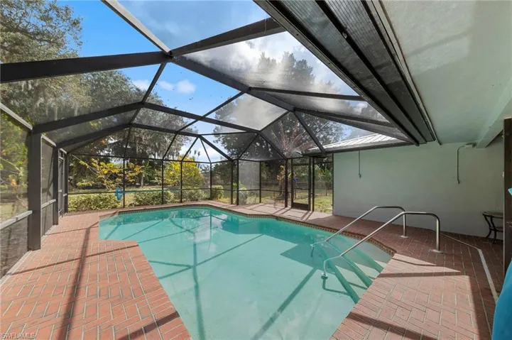 Outdoor pool with a patio, a sunroom, and a lanai