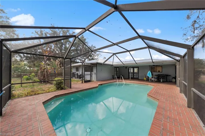Swimming pool with a sunroom, a lanai, a patio, and french doors