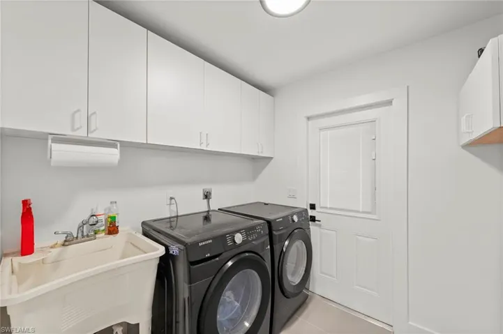 Laundry room featuring cabinet space, washing machine and dryer, and light tile patterned floors
