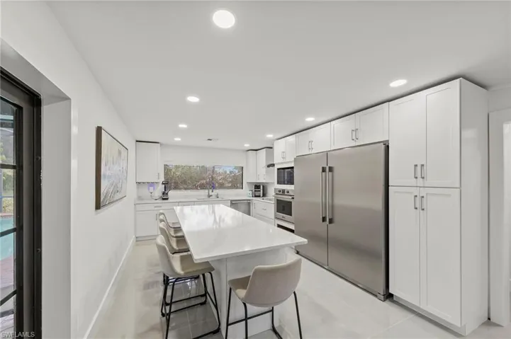 Kitchen featuring white cabinets, stainless steel appliances, a breakfast bar area, a center island, and recessed lighting