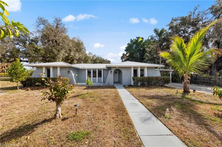 Ranch-style house with stucco siding, a front yard, a metal roof, and a carport