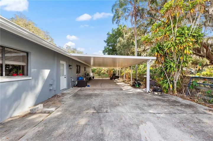 View of parking with concrete driveway and a carport