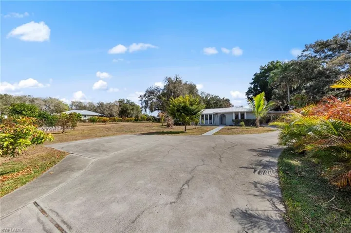 View of grassy yard featuring concrete driveway