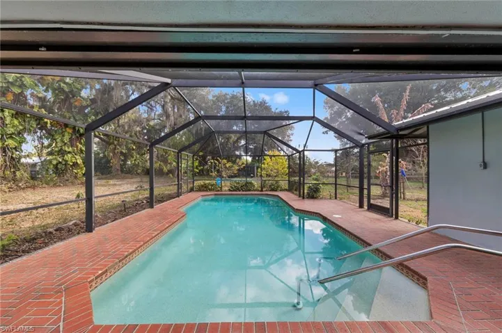 Swimming pool with a patio area, a sunroom, and a lanai