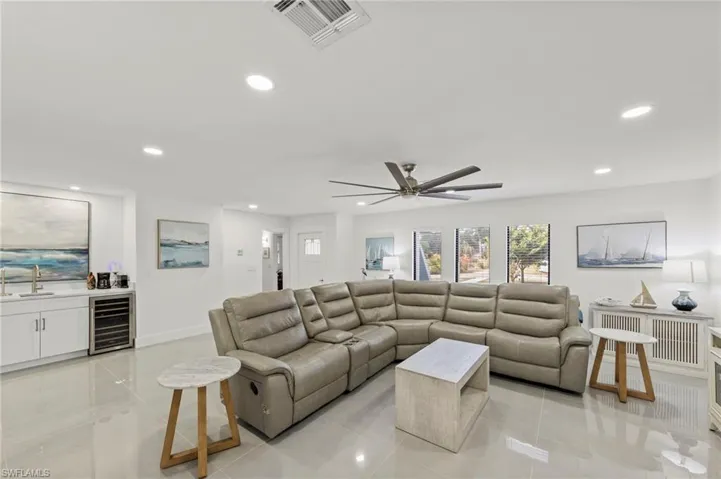 Living room with wine cooler, light tile patterned flooring, bar with sink, cooling unit, and recessed lighting