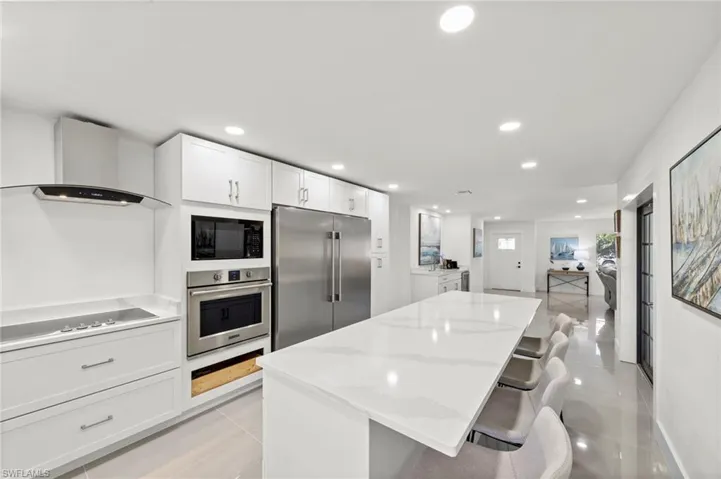 Kitchen with white cabinetry, a kitchen bar, recessed lighting, a kitchen island, and black appliances