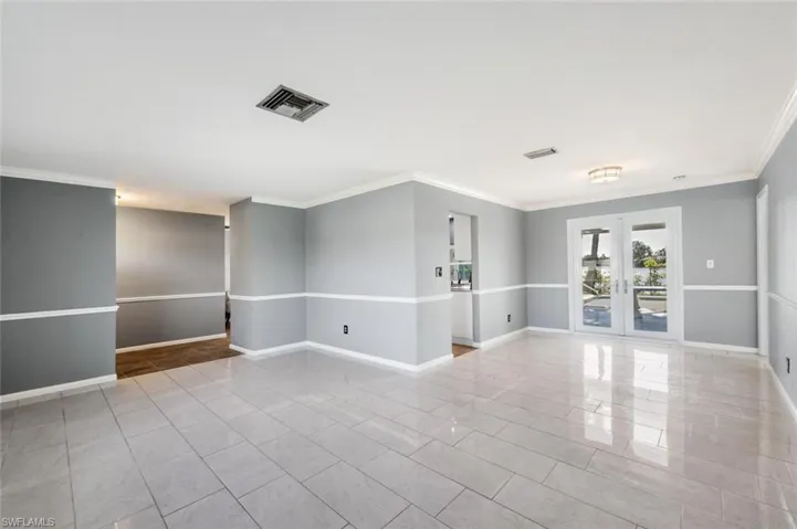 Living dining area with neutral floors and french doors to lanai