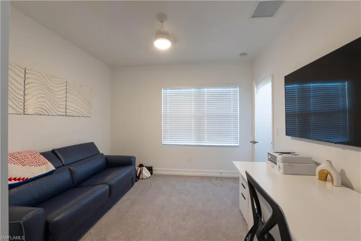 Living area with light carpet and a desk