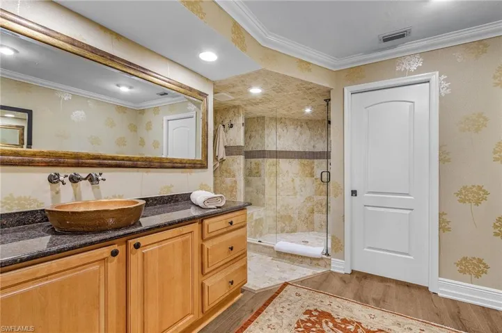 Bathroom featuring a shower stall, wood finished floors, vanity, ornamental molding, and visible vents