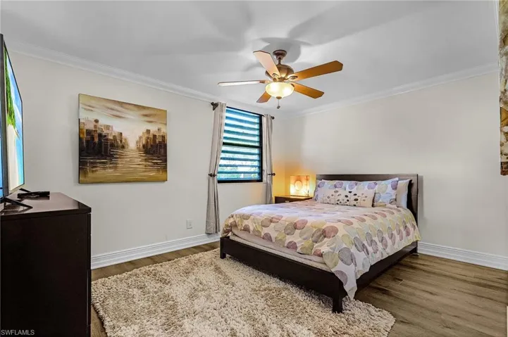 Bedroom with wood finished floors, baseboards, and ornamental molding