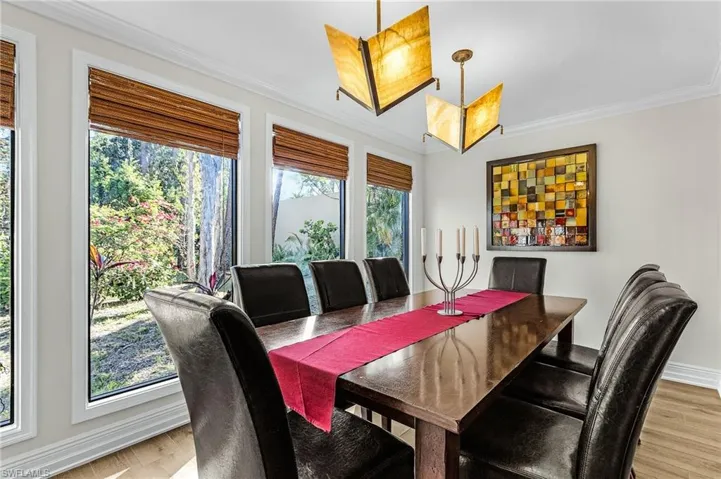 Dining area with light wood-type flooring, a wealth of natural light, and crown molding