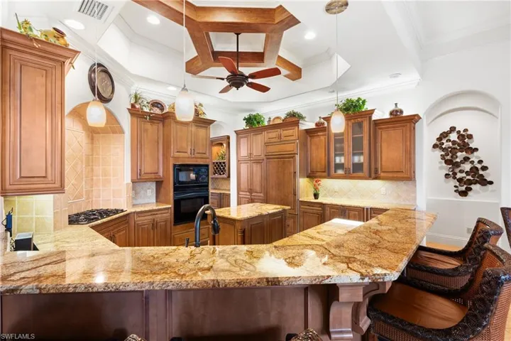 Kitchen with decorative light fixtures, decorative backsplash, black appliances, and kitchen peninsula