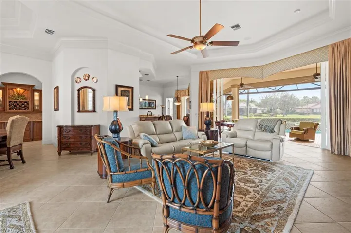 Tiled living room featuring crown molding, ceiling fan, and a raised ceiling