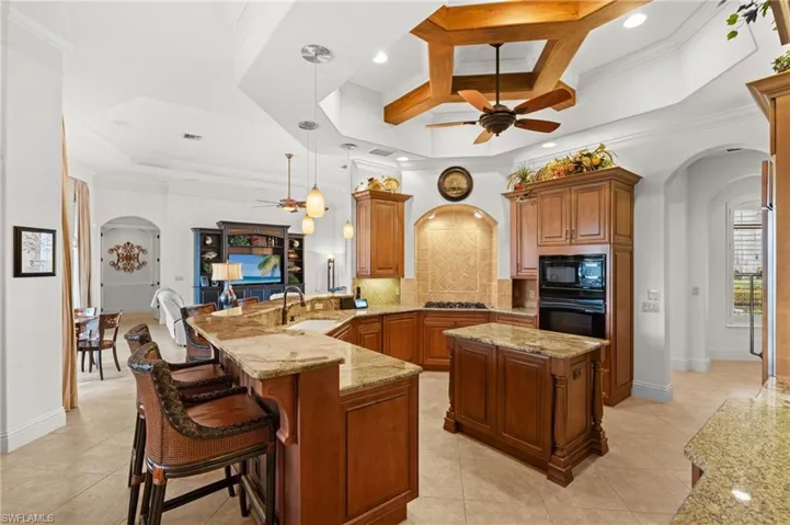 Kitchen featuring kitchen peninsula, hanging light fixtures, sink, coffered ceiling, and black appliances