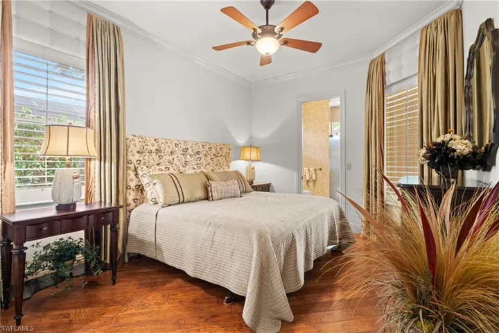 Bedroom with ceiling fan, crown molding, dark hardwood / wood-style floors, and ensuite bath