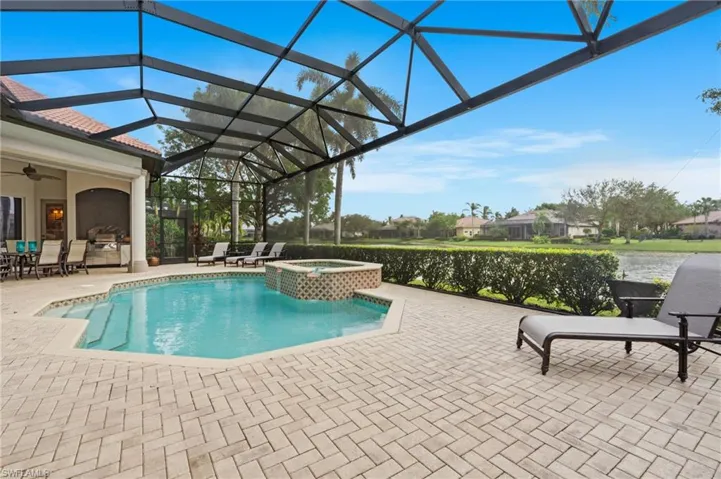 View of pool featuring ceiling fan, an in ground hot tub, a water view, a lanai, and a patio area