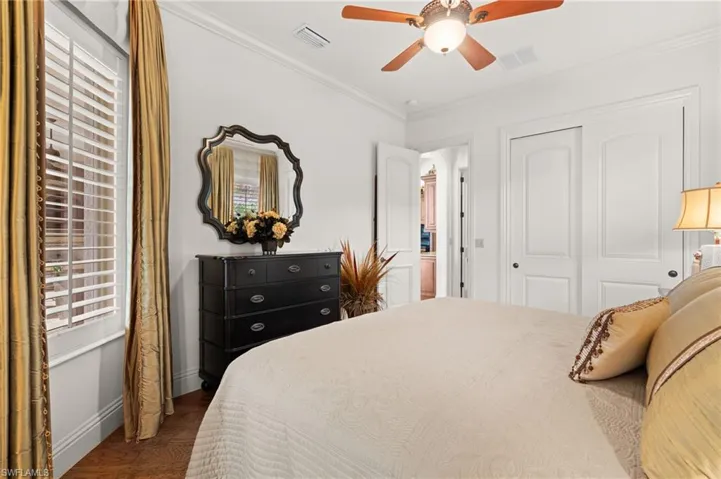 Bedroom featuring ceiling fan, dark wood-type flooring, a closet, and crown molding