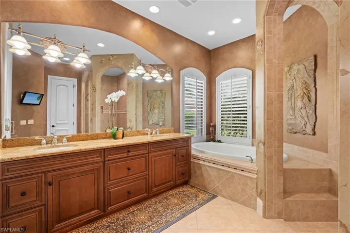 Bathroom with tiled tub, tile patterned floors, and vanity