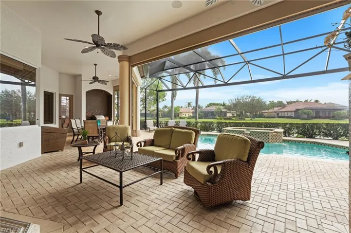 View of patio featuring glass enclosure, an outdoor living space, ceiling fan, a water view, and a swimming pool with hot tub