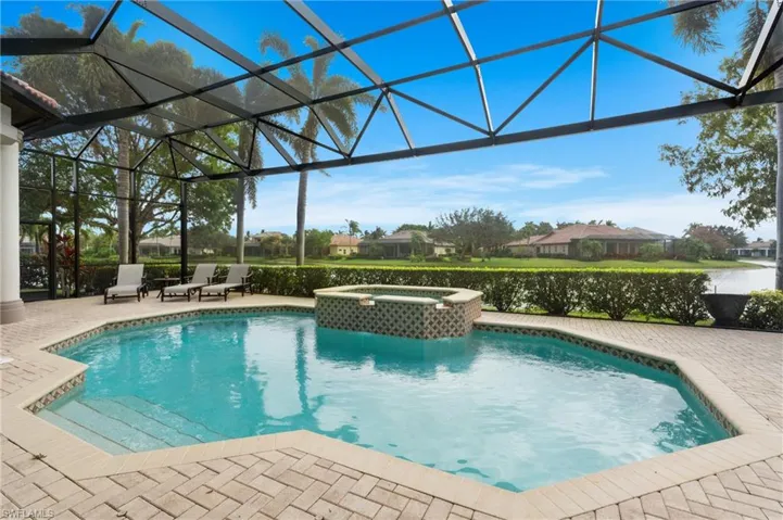 View of pool featuring glass enclosure, a patio area, and an in ground hot tub