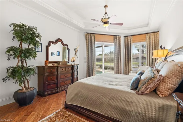 Bedroom with ceiling fan, hardwood / wood-style floors, ornamental molding, and a raised ceiling